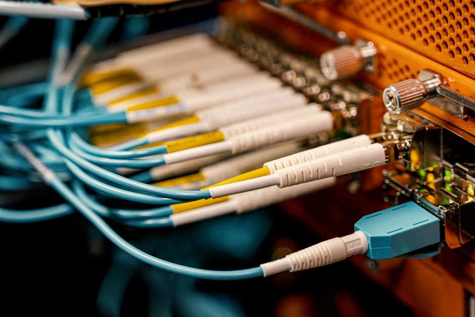 From above of optical switch equipment with many similar connectors with rubber cables and metal parts.